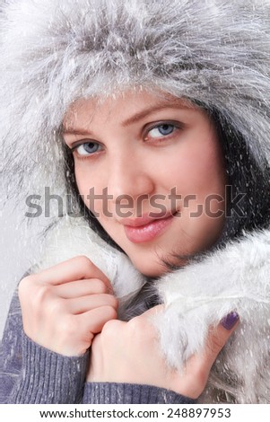 Beautiful Face of young woman wearing winter gloves covered with snow flakes (close up)