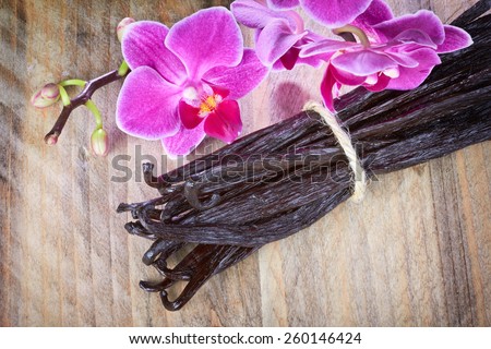 Vanilla sticks and orchid flower on the wood background