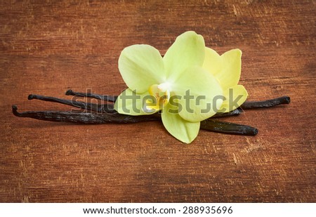 Vanilla sticks and yellow orchids on the wood background
