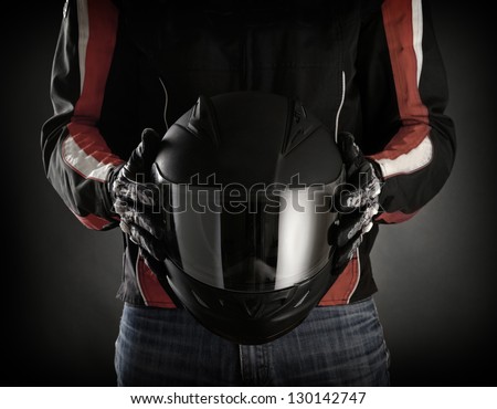 Motorcyclist with helmet in his hands.  Dark background