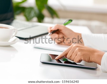 Woman hands with tablet PC and notepad at office