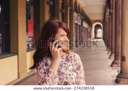 Smiling young girl talking on mobile phone in a city .Young smiling student girl outdoors talking on cell smart phone.Life style.City