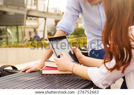 Smiling young woman student taping on tablet in a city on university.Young smiling student outdoors  with tablet.Life style.City