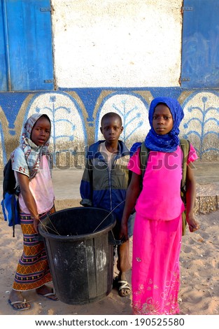 CARABANE,SENEGAL-APRIL 15, 2014: Children clean the school and carry a pail with garbage on April 15, in Carabane-Senegal.