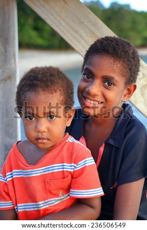 PANGI,VANUATU-OCTOBER 14, 2014: Native boy takes care of his brother while their parents work in a local business on October 14, in Pentecostes-Vanuatu.