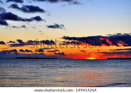 beautiful seascape with a remote island and iridescent clouds
