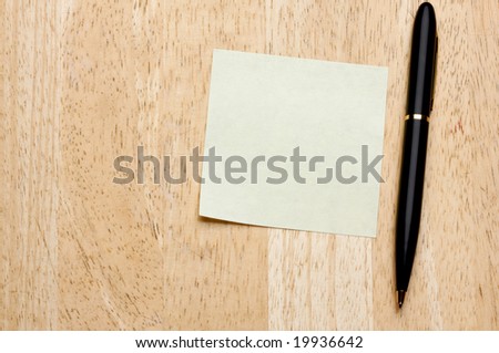 Pen and Post It Notes Pad Against a Wood Background