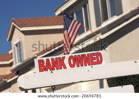Bank Owned Real Estate Sign and House with American Flag in the Background.