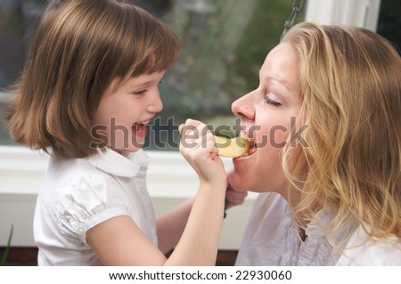 Daughter Having Fun Feeding Mom an Apple Slice