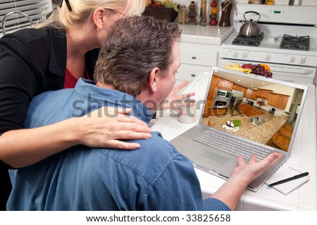 Couple In Kitchen Using Laptop to Research Home Improvement Ideas. Screen image can easily be replaced using the included clipping path.