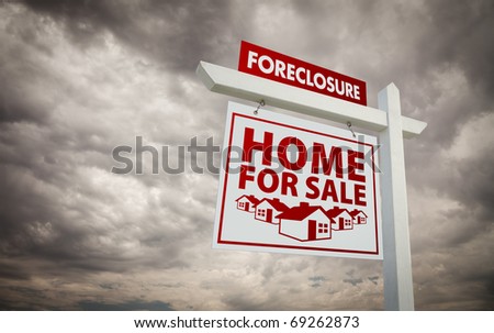 White and Red Foreclosure Home For Sale Real Estate Sign Over Ominous Cloudy Sky.