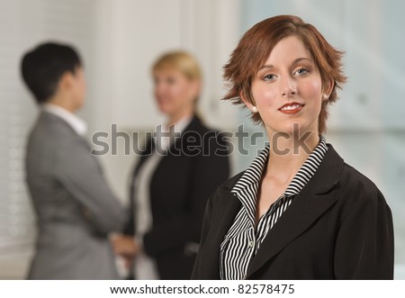 Pretty Red Haired Businesswoman with Colleagues Behind in an Office Setting.