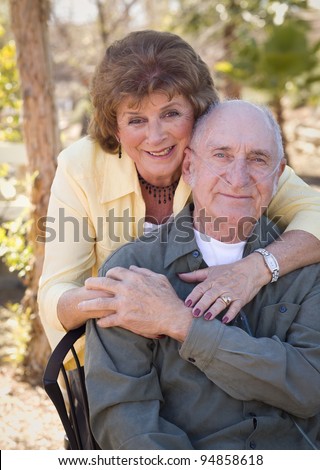 Senior Woman Outside with Seated Man Wearing Oxygen Tubes.