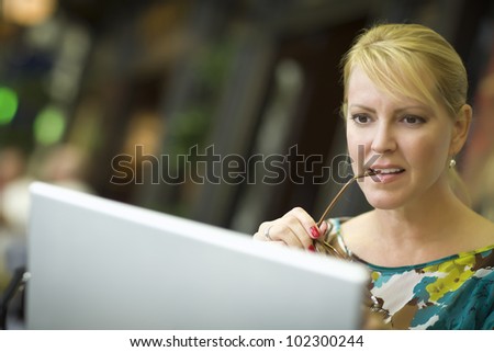 Beautiful Blonde Woman Using Her Laptop Computer in the City Lights.