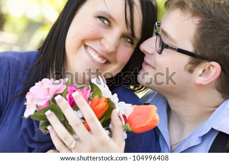Attractive Young Man Gives Flowers to His Fiance Wearing the Engagement Ring.