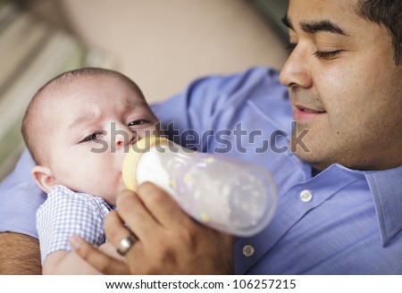 Happy Hispanic Father Bottle Feeding His Very Content Son.