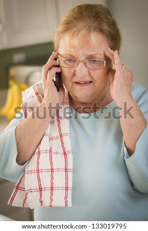 Shocked Senior Adult Woman on Her Cell Phone in Kitchen.