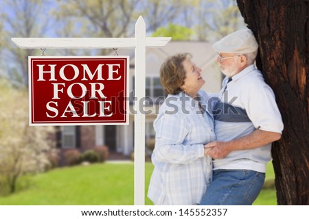 Home For Sale Real Estate Sign with Happy Affectionate Senior Couple Hugging in Front of House.
