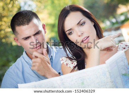 Lost and Confused Mixed Race Couple Looking Over A Map Outside Together.