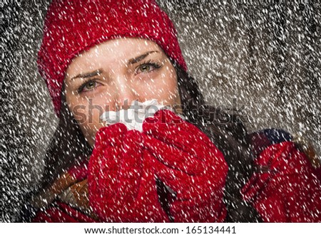 Sick Mixed Race Woman Wearing Winter Hat and Gloves Blowing Her Sore Nose with a Tissue in The Snow.