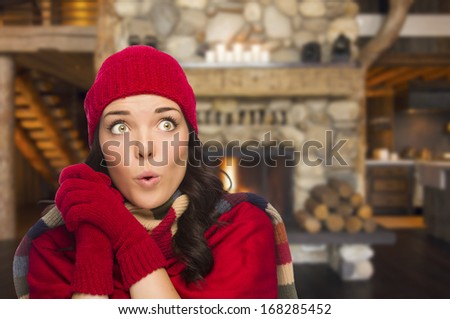 Smiling, Comfortable Mixed Race Girl Looking To The Side Enjoying Warm Fireplace In Rustic Cabin.