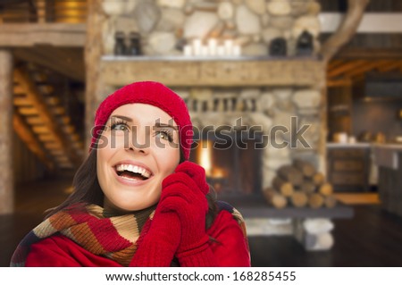 Smiling, Comfortable Mixed Race Girl Looking To The Side Enjoying Warm Fireplace In Rustic Cabin.