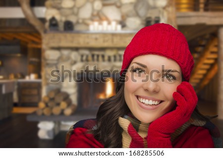 Smiling, Comfortable Mixed Race Girl Looking At Camera Enjoying Warm Fireplace In Rustic Cabin.