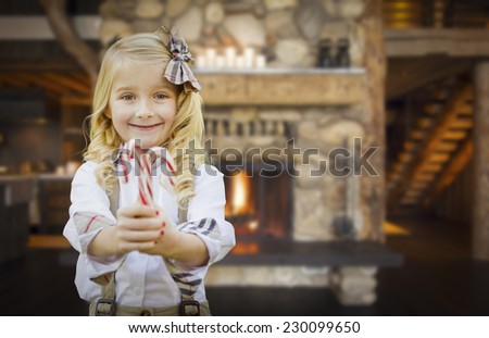 Cute Happy Young Girl Holding Candy Canes in Rustic Cabin.