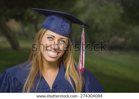 Smiling Young Woman Wearing Cap and Gown Outdoors.