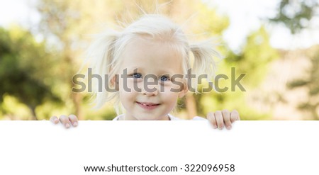 Cute Little Girl Outside Holding Edge of White Board with Room For Text.