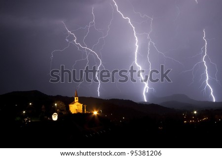 Night storm above a little chapel. Many lightning on the night sky.