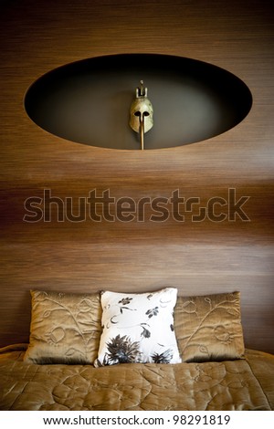 Part of a design bedroom with an ancient greek mask and pillows.