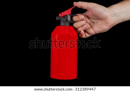 Human hand holding fire extinguisher and a blue flame isolated on black background