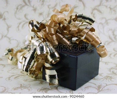 Shiny gold curly ribbons cascade off the side of a dark blue gift box.