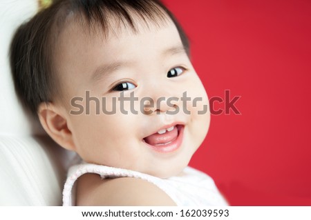 baby smiling and looking up to camera isolated on red background