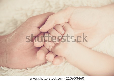 Closeup of baby hand into parents hands. Family concept