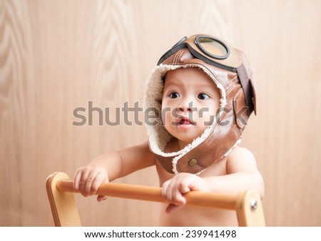 Image of one year old East Asian baby boy standing on wooden background, sweet little baby dreaming of being pilot