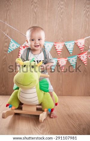 Boy sitting on dinosaurs. Birthday banner behind.Little asian boy celebrating first birthday