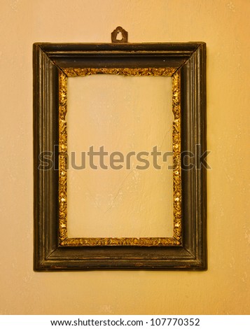 Old wooden empty frame hanging on a yellow wall