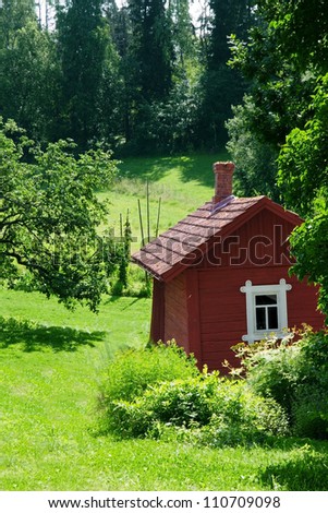 Small red idyllic farmhouse/ cottage in a sunny summer green landscape (Finland Scandinavia)