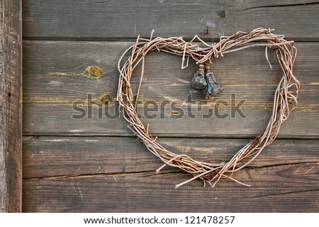 Rustic old handmade heart shaped wreath, hanging on a wooden wall exterior