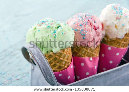 Three ice cream cones in a metal basket on blue wooden vintage background - stock photo