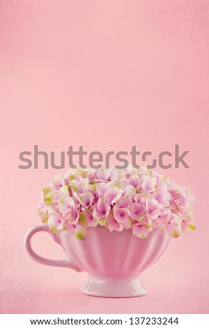 Pink hydrangea flowers in a shabby chic mug on pastel vintage background with copy space