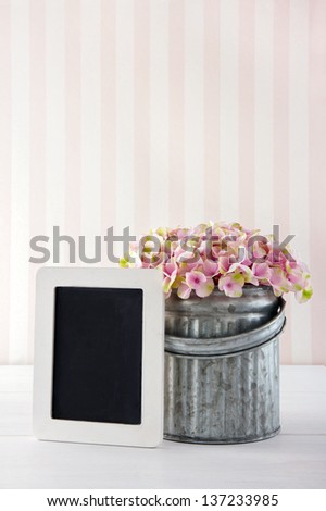 Pink hydrangea flowers in a metal vase on vintage background with empty blackboard for copy space