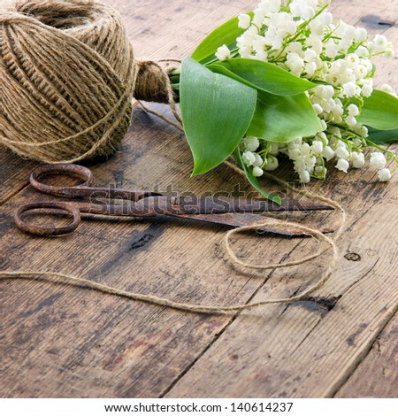 Bouquet of spring flowers lilys of the valley with old rusty antique scissors and ball of brown twine