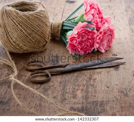 Bouquet of pink carnation flowers with old rusty antique scissors and ball of brown twine