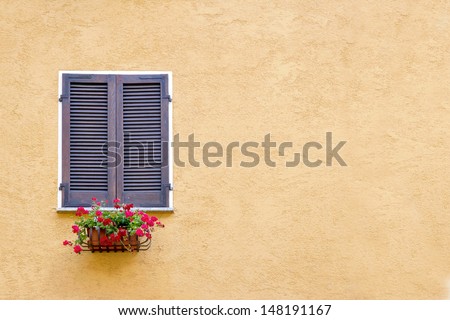 Old window with wooden shutters on yellow stucco wall and copy space