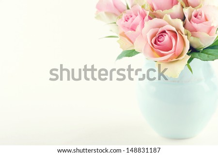 Pink roses in a light blue vase on cream beige shabby chic background with copy space