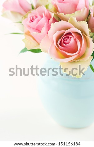 Pink roses in a light blue vase on cream beige shabby chic background with copy space