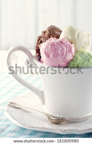 Scoops of ice cream in an elegant white cup on wooden rustic background with vintage hazy editing